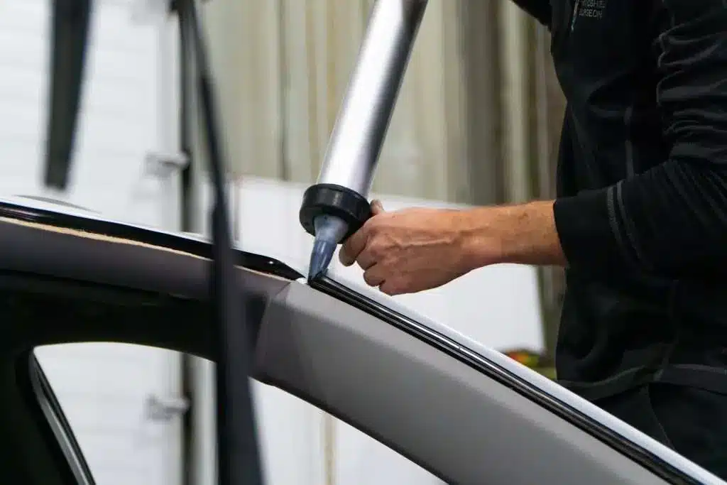 tech applying urethane to car during windshield replacement