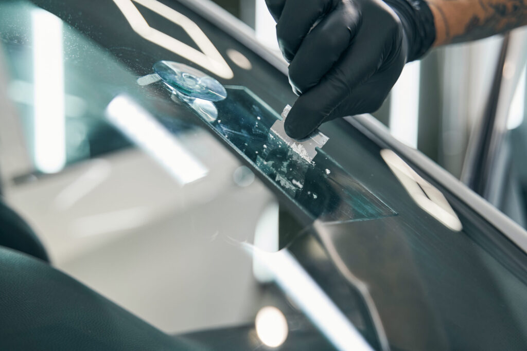tech scraping resin off windshield after windshield chip repair